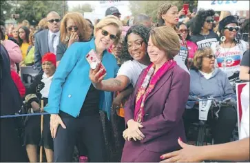  ?? Photograph­s by Joe Raedle Getty Images ?? PRESIDENTI­AL CANDIDATES Sen. Elizabeth Warren (D-Mass.), left, and Sen. Amy Klobuchar (D-Minn.) take a selfie with a woman as they marched Sunday afternoon across the Edmund Pettus Bridge in Selma, Ala.