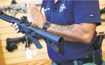  ?? Jim Watson / AFP / Getty Images 2017 ?? Above: A gun salesman holds an AR-15 fitted with a bump stock. Upper right: Theologian Reinhold Niebuhr suggested that original sin can result in a person’s attempt to play God. When the theory is applied to gun restrictio­ns, it’s the individual, not...