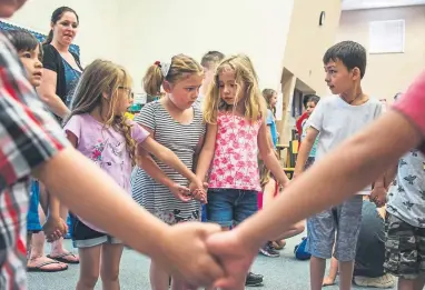  ?? Kelsey Brunner, The Denver Post ?? Children in a summer program at Lawrence Elementary School hold hands to form a circle at the start of craft time in Arvada on July 2.