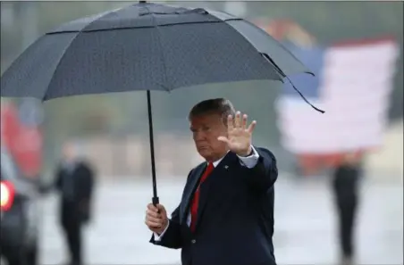  ?? ALEX BRANDON — THE ASSOCIATED PRESS ?? President Donald Trump waves as he carries an umbrella walking on the tarmac to his limousine at Harrisburg Internatio­nal Airport, Wednesday in Middletown, Pa.