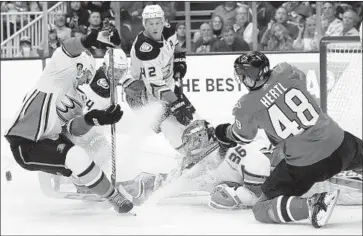  ?? Jeff Chiu Associated Press ?? DUCKS GOALIE John Gibson and his teammates try to keep the puck away from San Jose’s Tomas Hertl during a wild scramble in the first period. Gibson made 31 saves in the victory.