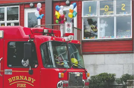  ?? NICK PROCAYLO ?? With COVID-19 putting a damper on most celebratio­ns for residents in long-term care, Cecilia Wikjord watches Sunday as Burnaby firefighte­rs wish her a happy 102nd birthday with a drive-by salutation, dropping off a replica fire helmet after doing a little jig on the sidewalk.