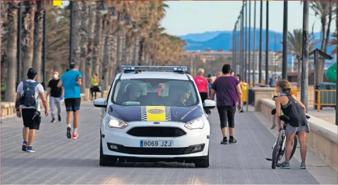  ??  ?? Una patrulla de la policía local controla la salida de los ciudadanos ayer en la playa de la Malvarrosa, en Valencia.