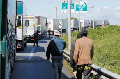  ?? (Pascal Rossignol/Reuters) ?? A FRENCH POLICEMAN signals to migrants to leave the road yesterday as trucks line up in Calais.