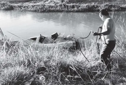  ?? FOTO: JOSÉ LACHICA ?? El chofer del servicio de arrastre utilizó una cadena para sacar la unidad del canal.