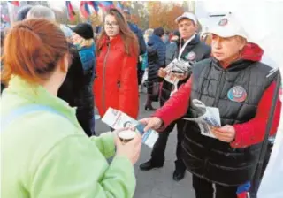  ?? AFP ?? Los activistas entregan folletos de Denis Pushilin en Donetsk