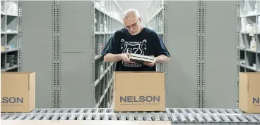  ?? LAURA PEDERSEN / NATIONAL POST ?? Brian VanDinther, an employee of Nelson, organizes textbooks for shipment Thursday in the Nelson warehouse in Toronto.