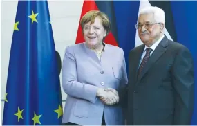  ?? (Pawel Kopczynski/Reuters) ?? GERMAN CHANCELLOR Angela Merkel shakes hands with PA President Mahmoud Abbas after issuing a statement in Berlin on Friday.