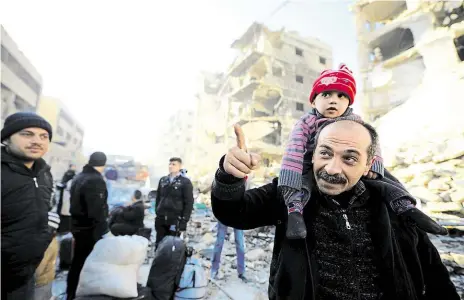  ?? Foto: Omar Sanadiki, REUTERS ?? Evakuace Syřané, kteří přišli z východního Aleppa, se rozhlížejí po ulici, již se svými jednotkami dobyl prezident Bašár Asad. Přinesli si jen těch pár věcí, které jim zbyly. Snímek z 9. prosince 2016.