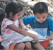  ??  ?? Estos dos pequeños felices abrieron sus paquetes escolares para escudriñar qué habían recibido.