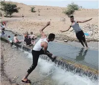  ?? MENAHEM KAHANA AFP/GETTY IMAGES ?? Palestinia­n youths play at a water spot near the occupied West Bank village of al-Auja in the Jordan valley on Friday.