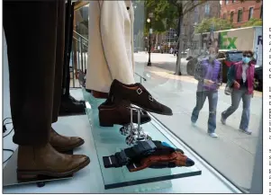  ?? (AP/Steven Senne) ?? Passers-by examine a storefront window Tuesday in Boston’s Newbury Street shopping district. Clothing sales climbed nearly 3% in August but were down 20% from a year earlier.