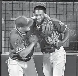  ?? Jayne Kamin-Oncea Getty Images ?? BRIAN GOODWIN is congratula­ted by Mike Trout after catching a ball hit by Ronald Guzman of Texas at the left-field wall in the fourth inning.