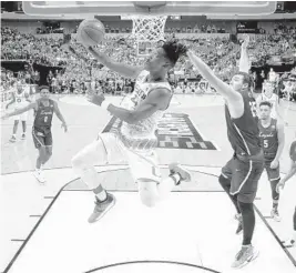  ?? PHOTOS BY RONALD MARTINEZ/GETTY IMAGES ?? Lonnie Walker IV (4), of the Miami Hurricanes, goes up for a shot against Cameron Krutwig (25), of the Loyola Ramblers, on Thursday.