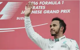  ?? — AFP ?? SUZUKA: Third-placed Mercedes AMG Petronas F1 Team’s British driver Lewis Hamilton waves his hand as he arrives at the podium after the Formula One Japanese Grand Prix at the Suzuka Circuit yesterday.