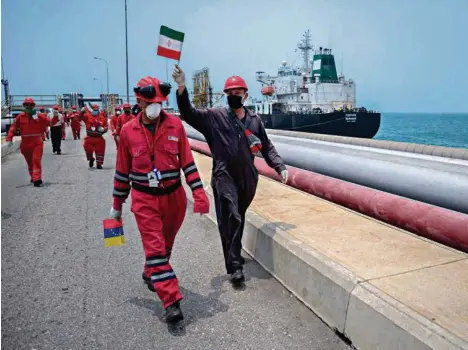  ?? (AFP) ?? Un ouvrier de la compagnie pétrolière vénézuélie­nne agite un drapeau de l’Iran à l’arrivée d’un pétrolier iranien à la raffinerie d’El Palito, dans l’Etat de Carabobo.
