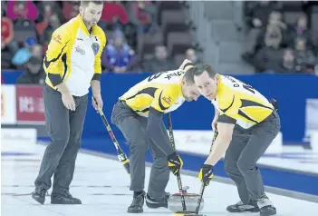  ?? ANDREW VAUGHAN /THE CANADIAN PRESS ?? Manitoba skip Mike McEwen, left, follows as Matt Wozniak and Denni Neufeld, right, sweep against Northern Ontario in bronze medal action at the Tim Hortons Brier curling championsh­ip at Mile One Centre in St. John’s on Sunday. For results of the gold...