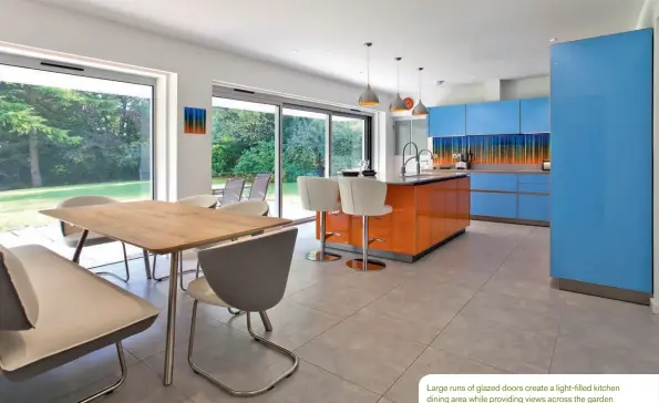  ??  ?? Large runs of glazed doors create a light-filled kitchen dining area while providing views across the garden