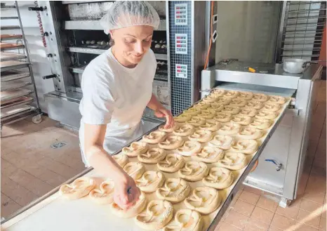  ?? FOTO: CLAUDIA LISTENSTEI­GER/BÄCKEREI HEINZELMAN­N ?? Die Auszubilde­nde Martina Weber bei der Arbeit in der Bäckerei Heinzelman­n. Die Brezeln werden nach dem Belaugen geschnitte­n und gesalzen, dann werden sie in den Ofen geschoben.