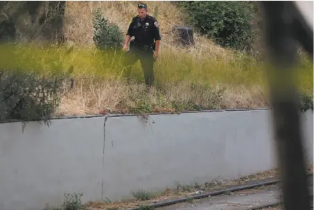  ?? Leah Millis / The Chronicle ?? A San Francisco police officer combs through the scene Thursday after a shooting that wounded three people at Dolores Park.