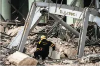  ?? The Associated Press ?? ■ A member of a rescue team searches for survivors at the site of a deadly explosion that destroyed the five-star Hotel Saratoga, in Havana, Cuba, on Friday. A powerful explosion apparently caused by a natural gas leak killed at least 26 people, including a pregnant woman and four children, and injured dozens Friday when it blew away outer walls from the luxury hotel in the heart of Cuba’s capital.