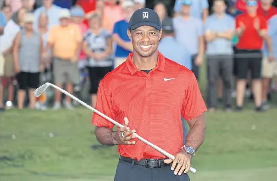  ??  ?? Tiger Woods holds the trophy after winning the Tour Championsh­ip.