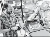  ?? Josh Edelson For The Times ?? JOSH GOLDBERG of Zume Pizza in Mountain View, Calif., uses a robot to move a pizza to an oven.