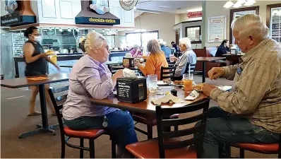  ?? Staff photo by Junius Stone ?? ■ Diners enjoy their lunch Thursday at Golden Corral in Texarkana, Texas. The reopened restaurant has its popular buffet, but instead of dishing the food out for yourself, now a server wearing a mask will put it on your plate. Seating capacity is still governed by social distancing restrictio­ns.