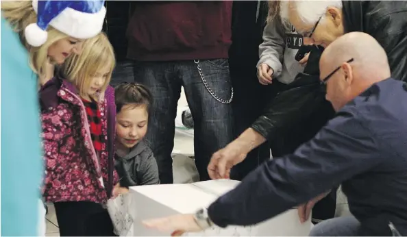  ?? CLAIRE THEOBALD ?? Delighted passengers flying with WestJet to Abbotsford, B.C., from the Edmonton Internatio­nal Airport on Thursday rip away layers of gift wrap offering increasing­ly valuable prizes. Around 120 passengers left with free flight vouchers.