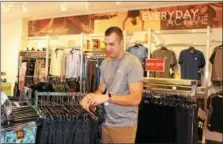  ?? MICHILEA PATTERSON — DIGITAL FIRST MEDIA ?? Justin Meade, manager of the local active wear RBX retail store, hangs clothes. The store was recently opened inside the Philadelph­ia Premium Outlets in Limerick.