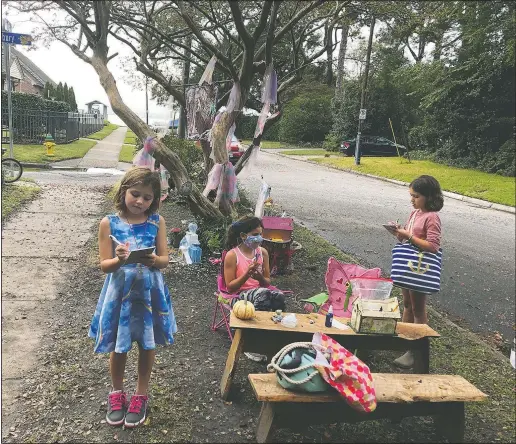  ?? (AP/Ben Finley) ?? Maya Gebler (center), Cate and Sophie Carroll (right) write letters to fairies in Norfolk, Va., on Oct. 12. In the last few months, more than 700 letters have arrived at a fairy tree village outside the home of a journalist and children’s book author.