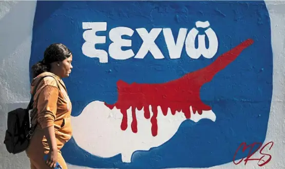  ?? afp ?? a woman walking past graffiti depicting a map of Cyprus on a wall in Nicosia. —