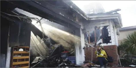  ?? AP PhOtO/MArcIO JOSe SAnchez ?? Calib Willis of the Los Angeles County Fire Department hoses down a smoldering residence destroyed by a wildfire on Friday in Santa Clarita, Calif.