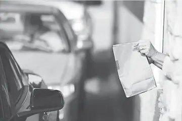  ??  ?? A worker passes a bag of food to a customer at the drive-thru window at a McDonald’s in White House, Tennessee, on Jan 18.