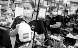  ?? JOE RAEDLE/GETTY ?? Cashiers ring up groceries amid the pandemic April 13 at a supermarke­t in Miami.