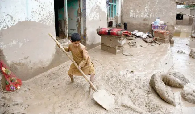  ?? Agence France-presse ?? ↑
An Afghan boy shovels mud from the courtyard of his house following flash floods after heavy rainfall at a village in Baghlan-e-markazi district of Baghlan on Sunday.