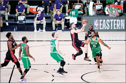  ?? (AP) ?? Miami Heat guard Goran Dragic (7) takes a shot after getting through the defense of Boston Celtics’ Gordon Hayward (20) and Jayson Tatum (0) during
the first half of Game 4 of an NBA basketball Eastern Conference final on Sept 23, in Lake Buena Vista, Fla.