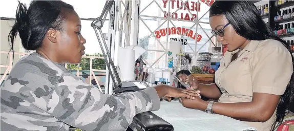  ??  ?? Owner of Glamorous Beauty Parlour, Sashagaye Richards (right) tends to a customer.