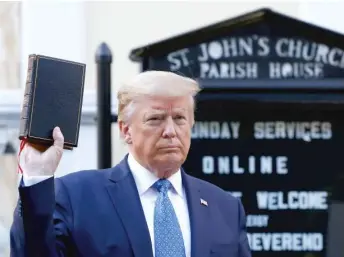  ?? PATRICK SEMANSKY/AP ?? President Donald Trump holds a Bible on Monday outside St. John’s Church across from the White House after peaceful protesters were forcefully moved to clear Trump’s path.