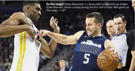  ??  ?? Do the tango: Dallas Mavericks’ J. J. Barea (left) is defended by Golden State Warriors’ Kevon Looney during the first half of their NBA game on Thursday. — AP