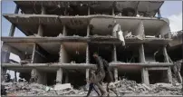  ?? MOHAMMED DAHMAN — THE ASSOCIATED PRESS ?? Palestinia­ns walk through destructio­n after Israeli forces left Khan Younis, Gaza Strip, on March 6.