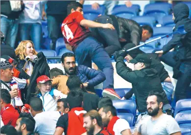  ?? ROBERT PRATTA / REUTERS ?? Besiktas and Lyon fans clash in the stands during the UEFA Europa League quarterfin­al first-leg match at Parc Olympique Lyonnais in Lyon, France, on Thursday. The start of the match, which Lyon won 2-1, was delayed 45 minutes.