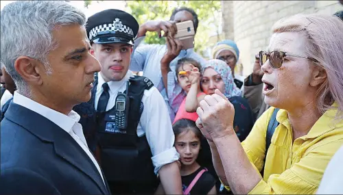  ??  ?? Outburst: Sadiq Khan listens as a woman in the crowd confronts him during his visit to the disaster area yesterday