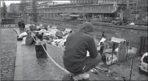  ?? The Associated Press ?? MAKESHIFT CAMP: Migrants sit by a makeshift camp on Thursday in Paris. The French government is scrambling to meet President Emmanuel Macron’s deadline to get migrants off France’s streets by year’s end.