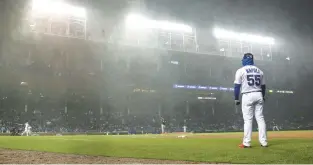  ?? CHRIS SWEDA/CHICAGO TRIBUNE ?? Cubs first base coach Mike Napoli watches as a chilly rain falls during a game against the White Sox at Wrigley Field on Tuesday night.