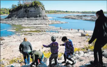  ?? Jeff Roberson The Associated Press ?? People walk toward Tower Rock to check out the attraction normally surrounded by the Mississipp­i River and only accessible by boat on Oct. 19 in Perry County, Mo.