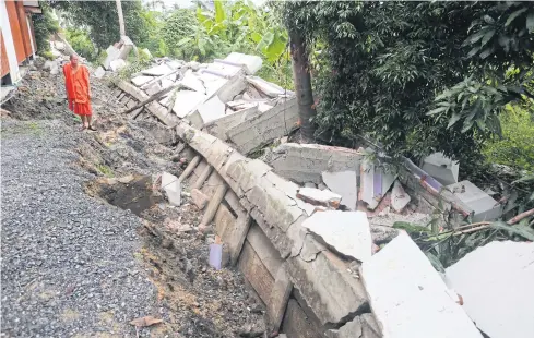  ?? CHATPATTAR­ASILL
PATTARAPON­G ?? Phra Khru Nonthakhun Piphat, the abbot of Wat Choeng Len in tambon Tha-it, Nonthaburi’s Pak Kret district, inspects the temple’s wall that has subsided due to heavy rain.