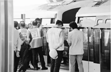  ??  ?? Staff from SMRT and Singapore’s Land Transport Authority gather around two trains that collided at a train station in Singapore. — AFP photo