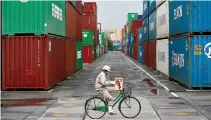  ?? REUTERS ?? A WORKER rides a bicycle in a container area at a port in Tokyo in this April 21, 2014 file photo.