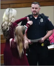  ?? Westside Eagle Observer/MIKE ECKELS ?? Decatur Police Officer Randy Deason (center) receives a ribbon from his wife while one of his daughters takes a photograph during the Decatur City Council meeting at city hall on Feb. 15. Deason received a commendati­on for saving the life of a...